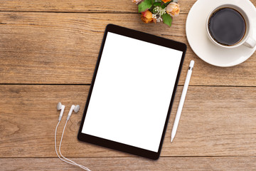 Mockup image of black tablet computer pc with blank white screen ,pencil and earplug with cup of hot black coffee on wooden table background.  Top view. Flat lay. 