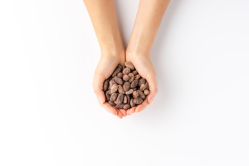 Overhead shot of woman’s hands holding cocoa beans isolated on white background