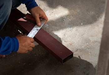 Close-up Of construction worker's hands are measuring steel box.