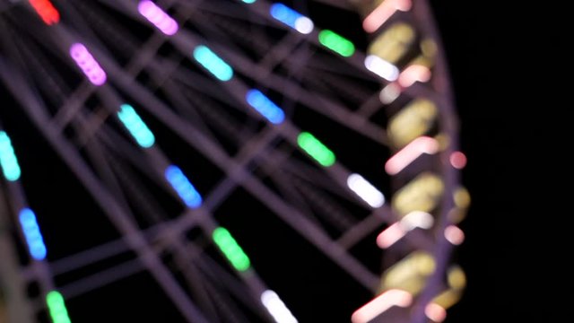 Bokeh Close up shot showing slowly spinning ferris wheel at night on fun fair,steady