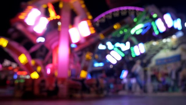 Wide shot of lighting up carousel machine arms spinning sitting people,static
