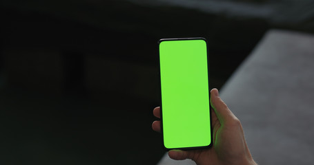 man use smartphone with green screen while lying on a couch