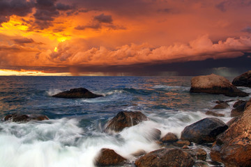 Sunset on the rocky shore of tropical sea