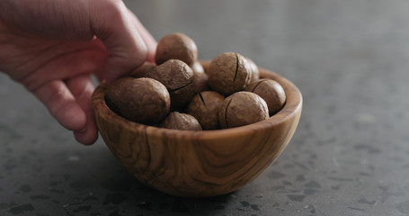 man hand bowl full of macadamia nuts on terrazzo countertop