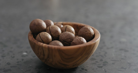 inshell macadamia nuts in olive wood bowl on terrazzo surface