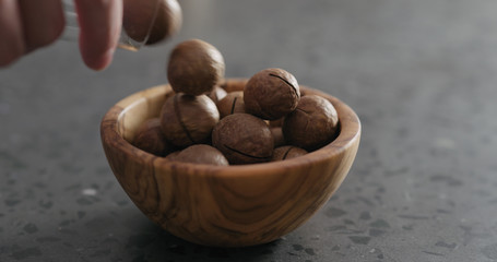 inshell macadamia nuts fall into olive wood bowl