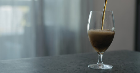 pour stout beer into tulip glass on terrazzo countertop with copy space