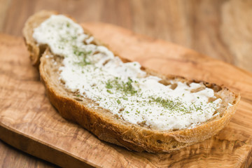 crunchy rustic bread with ricotta and herbs on olive wood board