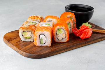 Japanese food. Sushi rolls with salmon, cream cheese, cucumber and other served on wood plate with soy sauce, ginger and wasabi