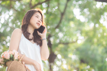 Asian women talking cellphone in city public park