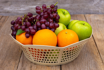 Various types of fruit: orange,grapefruit and green apple in basket isolated on wood table background. Health fruits and healthcare concept.