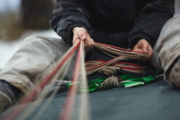 Base jumper packing the parachute before jumping close-up. Face is not visible. Parachute equipment.