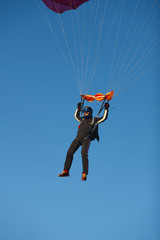Skydiver under the canopy of the parachute against a blue sky on a sunny day, close-up. Parachute jumps.