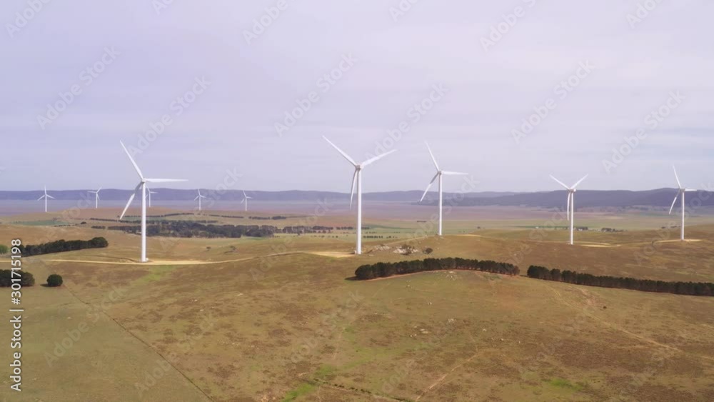 Wall mural aerial view of an array of large wind turbines rotating to create kinetic energy for renewable energ