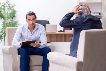 Old man visiting young male doctor psychologist