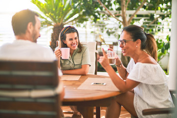 Beautiful family sitting on terrace drinking cup of coffee speaking and smiling