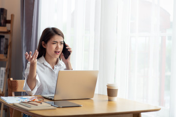 Serious concerned Young Asian business woman arguing while talking on phone