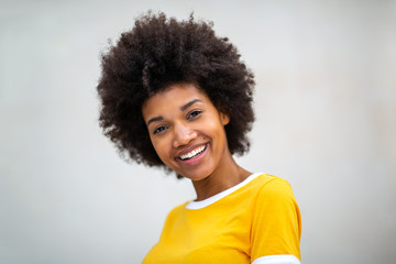 Close up of beautiful young black woman smiling by white background