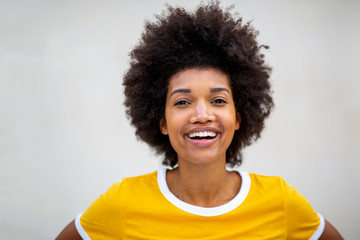 Close up of beautiful young black afro woman smiling by white background