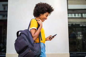 Side of young black woman walking with cellphone and bag
