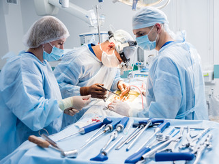 Spinal surgery. Group of surgeons in operating room with surgery equipment. Laminectomy