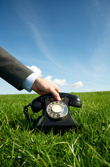 Hand of unrecognizable businessman grasping the receiver of an old-fashioned black rotary dial...
