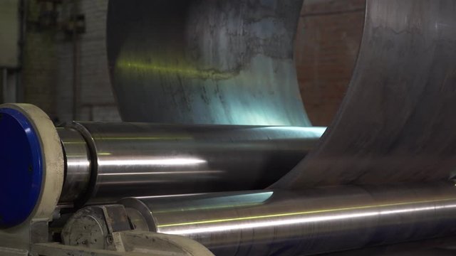 In old production, huge machines twist metal into flat pipe, process before welding, preparation of processed metal, industry, metal rolling, export products, obsolete production, heavy machinery