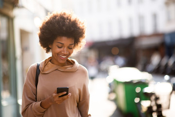 beautiful young black woman with phone walking in city