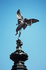 Statue of Anteros (brother of the Greek god Eros) standing in sunny blue sky at the top of the Shaftesbury Memorial Fountain erected 1892 in Piccadilly Circus, London, UK