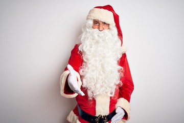 Middle age handsome man wearing Santa costume standing over isolated white background smiling friendly offering handshake as greeting and welcoming. Successful business.