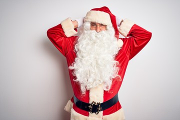 Middle age handsome man wearing Santa costume standing over isolated white background relaxing and stretching, arms and hands behind head and neck smiling happy