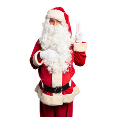Middle age handsome man wearing Santa Claus costume and beard standing smiling swearing with hand on chest and fingers up, making a loyalty promise oath