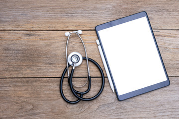 Mockup image of black tablet computer pc with blank white screen with pencil and medical stethoscope isolated on wood table background. Top view. Flat lay. Clipping path. Copy space for text.