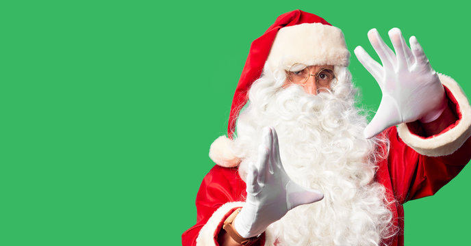 Middle age handsome man wearing Santa Claus costume and beard standing doing frame using hands palms and fingers, camera perspective