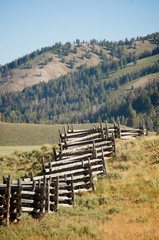 View of rustic stacked split rail fence zig zagging along a Western mountain desert ranch summer landscape in the Idaho Rockies