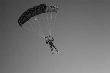 Skydiver under the canopy of a parachute against the background of the dark sky close-up. Skydiving. Stylization under the photo made on black-and-white film.