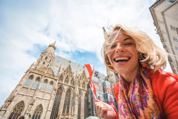 Papier Peint photo autocollant Vienne Woman stands on the background of St. Stephen's Cathedral in Vienna with the flag of Austria in hand, Austria