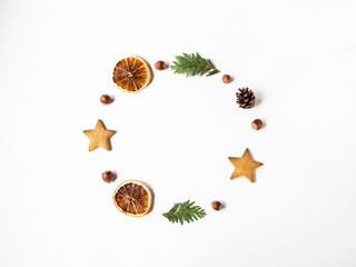 Flat lay Christmas circle frame composition - star cookie, nuts, dry orange slices, pine cone and fir branches on white background. top view, copy space