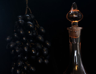 On a dark background a bunch of black grapes. Near the carafe for wine. Winemaking Concept