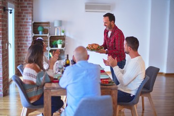 Beautiful family smiling happy and confident. Showing roasted turkey and applauding celebrating Thanksgiving Day at home