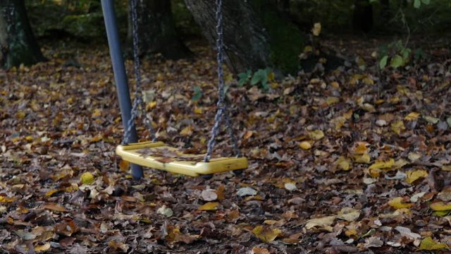Closeup of empty swing-set moving by itself; kidnapping and pedophile concept.