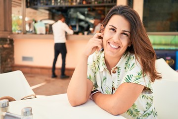 Young beautiful woman sitting at restaurant enjoying summer vacation