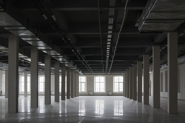 Empty huge open space in old factory building with rows of columns, big windows and pipes on the ceiling. Industrial or loft style background, mock up