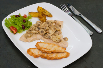 Braised champignons with fish fillet, salad, fried potatoes and croutons