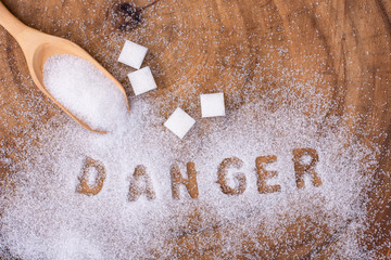 White sugar in wooden spoon and words 