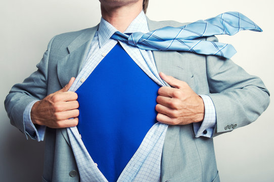 Superhero businessman pulling open his suit to reveal a bright blue shirt with blank copy space beneath