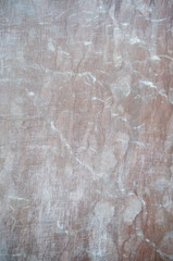 Marbled brown red stone background featuring light marks from cuts and scratches