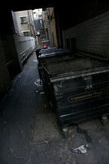 Dark view of dingy back alley with a British garbage dumpster in Soho, London
