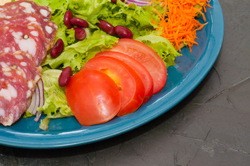 Salad with sausage, tomatoes, beans, carrots, spices, olive oil or sauce. Restaurant serving Italian food