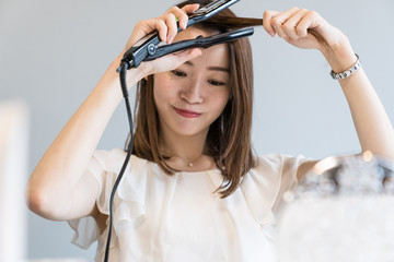 ヘアアイロンを使う女性